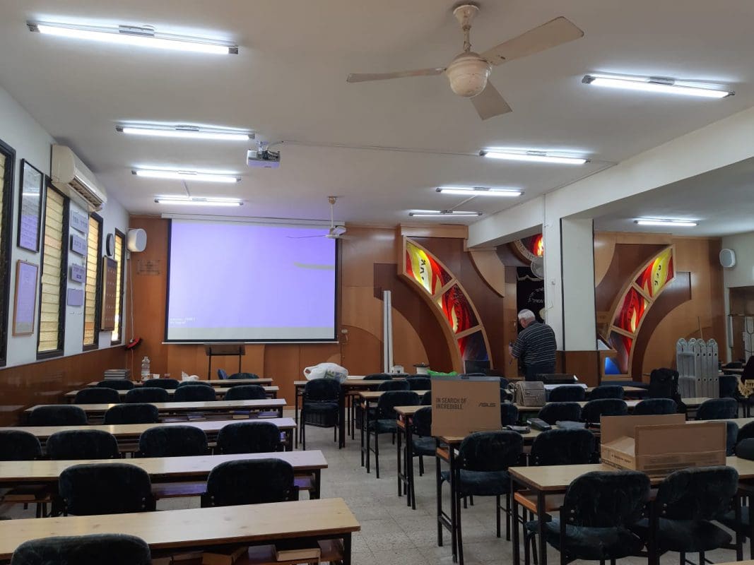 אודיטוריום עם מסך הקרנה גדול ומערכת סאונד מעל הבמה