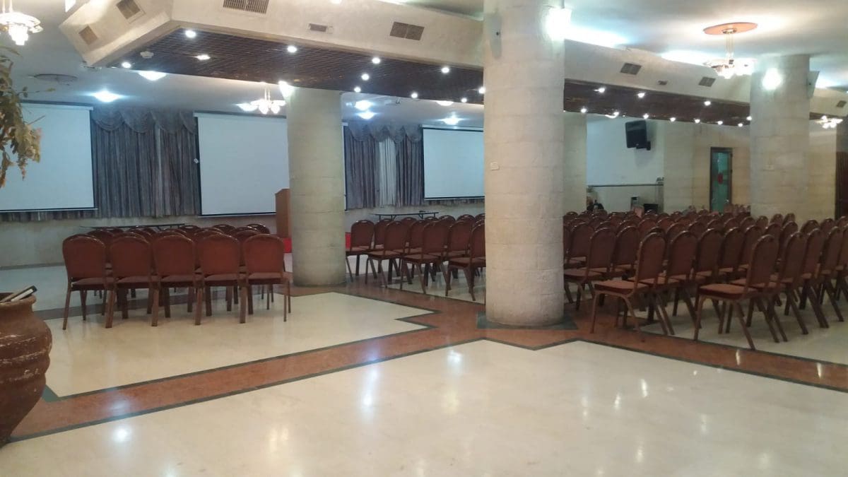 התקנת מסכי הקרנה באולם מוסדי עם תאורת תקרה ורמקולי קיר