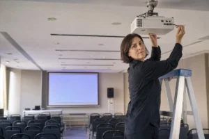מערכת שמע לבית או לעסק - א.א. מערכות מקרן לייזר מותקן בתקרת אולם כנסים, מתקין מהדק את המקרן לתושבת